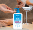 Dermal Therapy Acne Control Wash bottle on a bathroom counter with product being dispensed into a hand