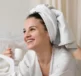 A woman with a towel on her head drinking a coffee - thinking how many skincare products do I need?