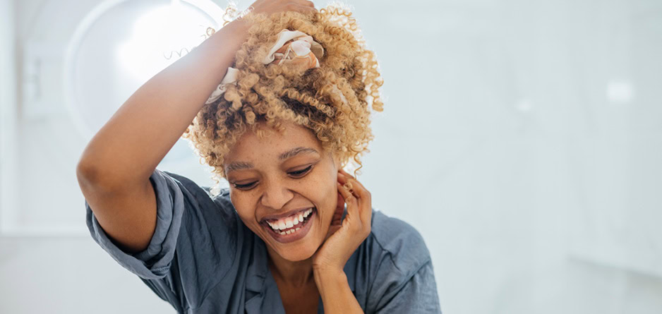 A woman with curly hair laughing finding relief with scalp relief shampoo