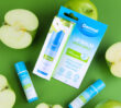 Dermal Therapy Lip Balm Green Apple packaging and sticks surrounded by whole and sliced green apples on a green background