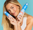 Image of a smiling model holding one of the Dermal Therapy Sebum Control Dry Shampoo on each hand