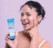 Liz Claire holding a Dermal Therapy product and applying cream to her cheek