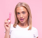 Tammy Hembrow holding a Tinted Lip Balm – Rose Pink on a pink background 