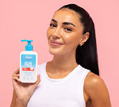 Yasmina Elmerkaoui holding a Dermal Therapy product on a peach background. 