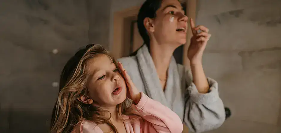 A woman and child applying eczema cream to their faces creating a simple eczema friendly skincare routine for kids