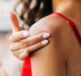 A woman in a red tank top applying Dermal Therapy Dry Skin products to her severe dry skin - Xerosis