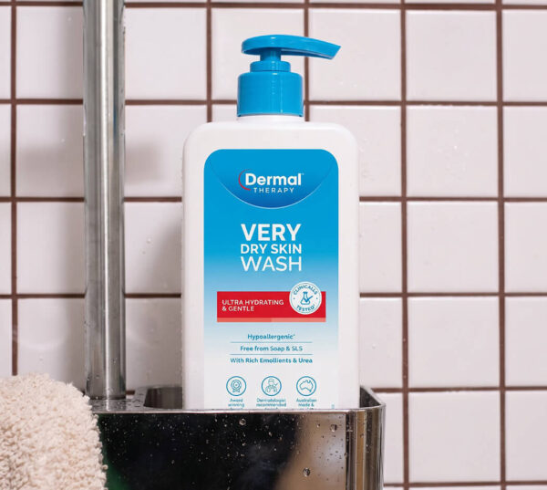 Dermal Therapy Very Dry Skin Wash pump bottle placed on a shower shelf against white tiled walls