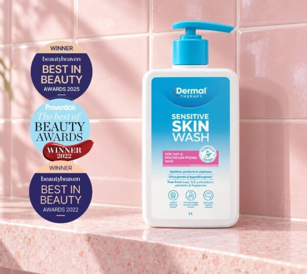 Bottle of Dermal Therapy Sensitive Skin Wash displayed on a pink tiled surface beside three award badges.
